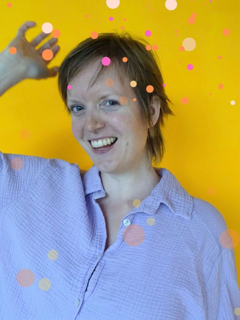Das Foto zeigt die Susanne, die Künstlerin und Website-Betreiberin. Es ist ein Portrait im Profil; sie trägt eine rosa Mütze und eine Wolljacke. Der Himmel im Hintergrund ist blau