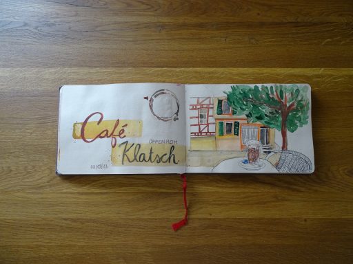 Aquarellzeichnung des Café Klatsch in Oppenheim am Rhein; ein Tisch mit einem Latte Macchiatoglas am Marktplatz; Fachwerkhäuser