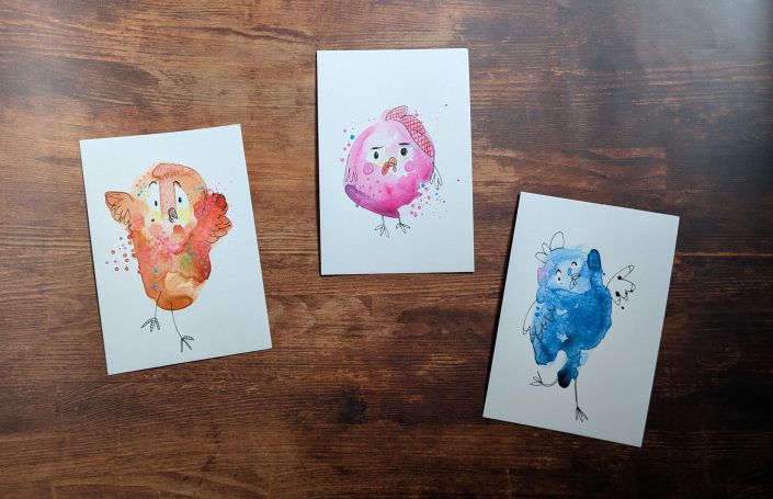 Dei verschiedene Pstkarten, auf denen jeweils ein Vogel in einer anderen farbe kunsthaft dargestellt wird